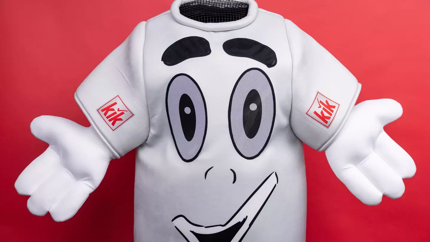 La mascotte a forma di maglietta KiK con le braccia aperte davanti alla fotocamera