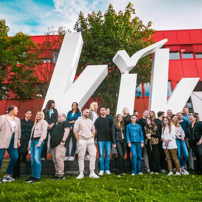 I dipendenti posano per una foto di gruppo davanti alla sede centrale europea di Bönen, con il grande logo KiK sullo sfondo